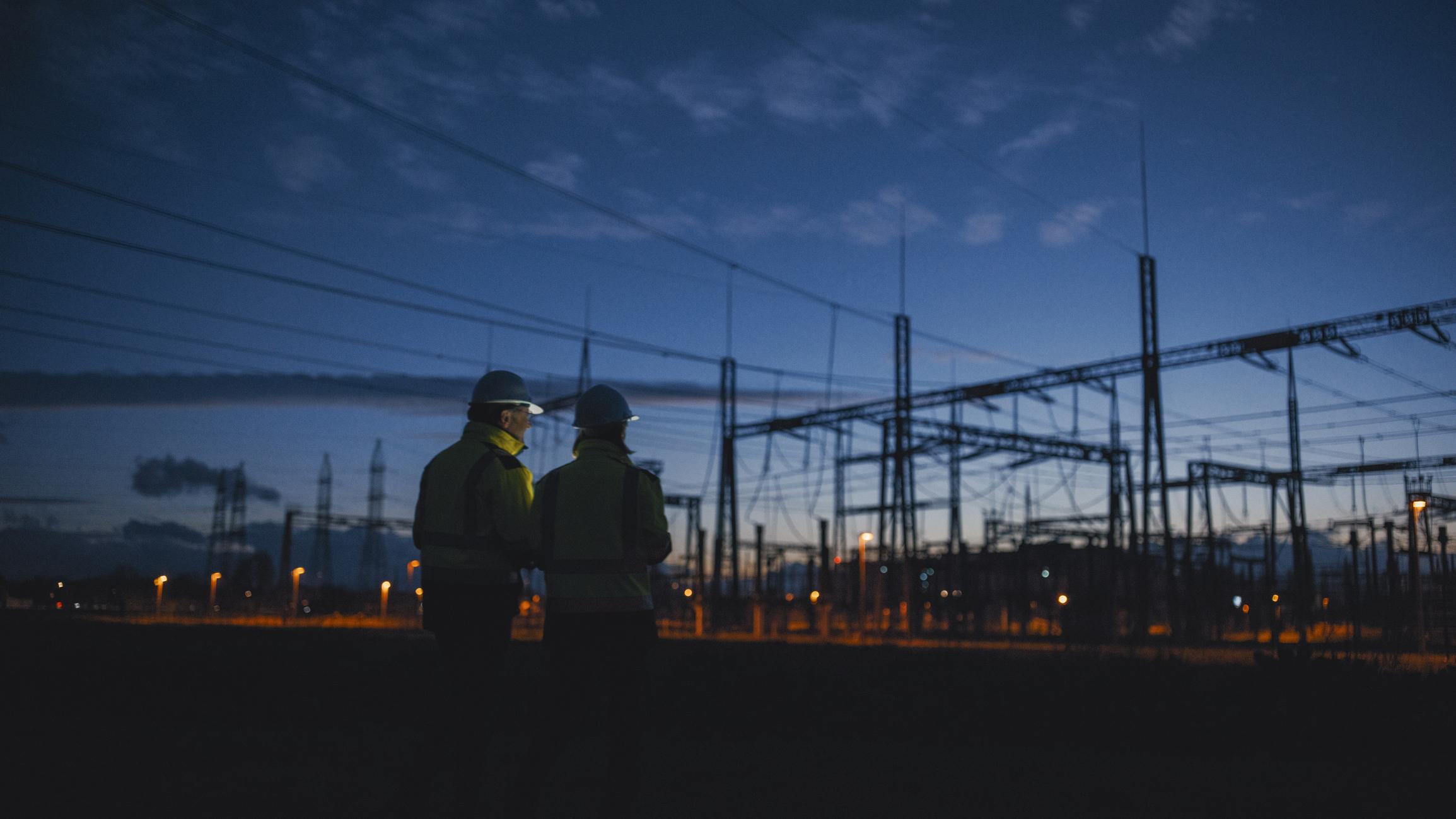 Workers' silhouettes at an electric plant at night