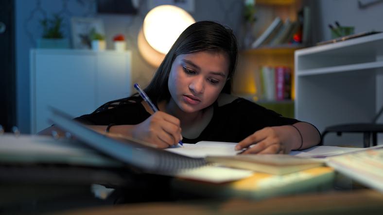 child working on homework at night with lights on