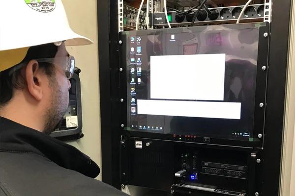 Man in a hardhat looking at a computer screen