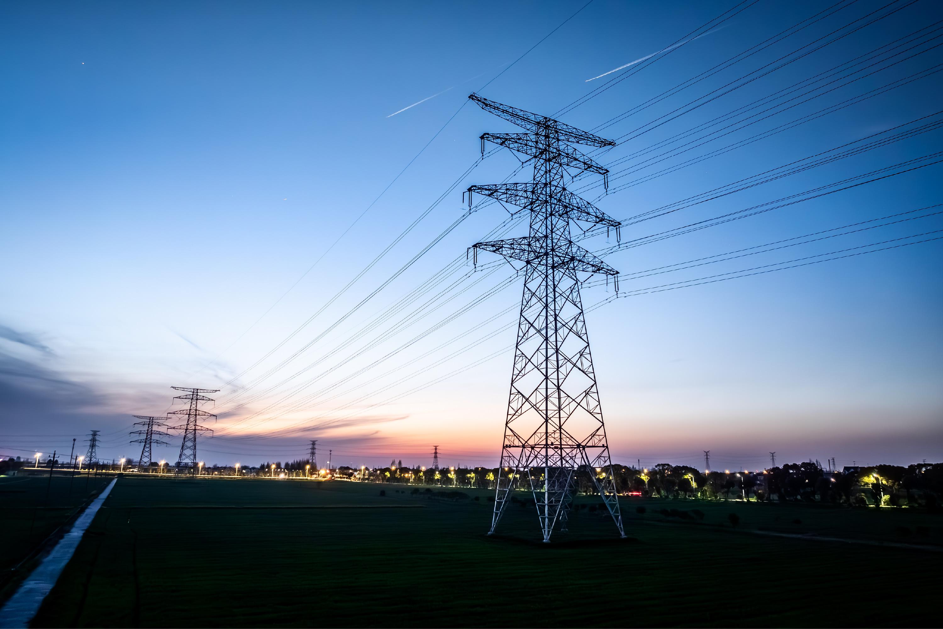 Powerlines with a cityscape behind them at dusk 